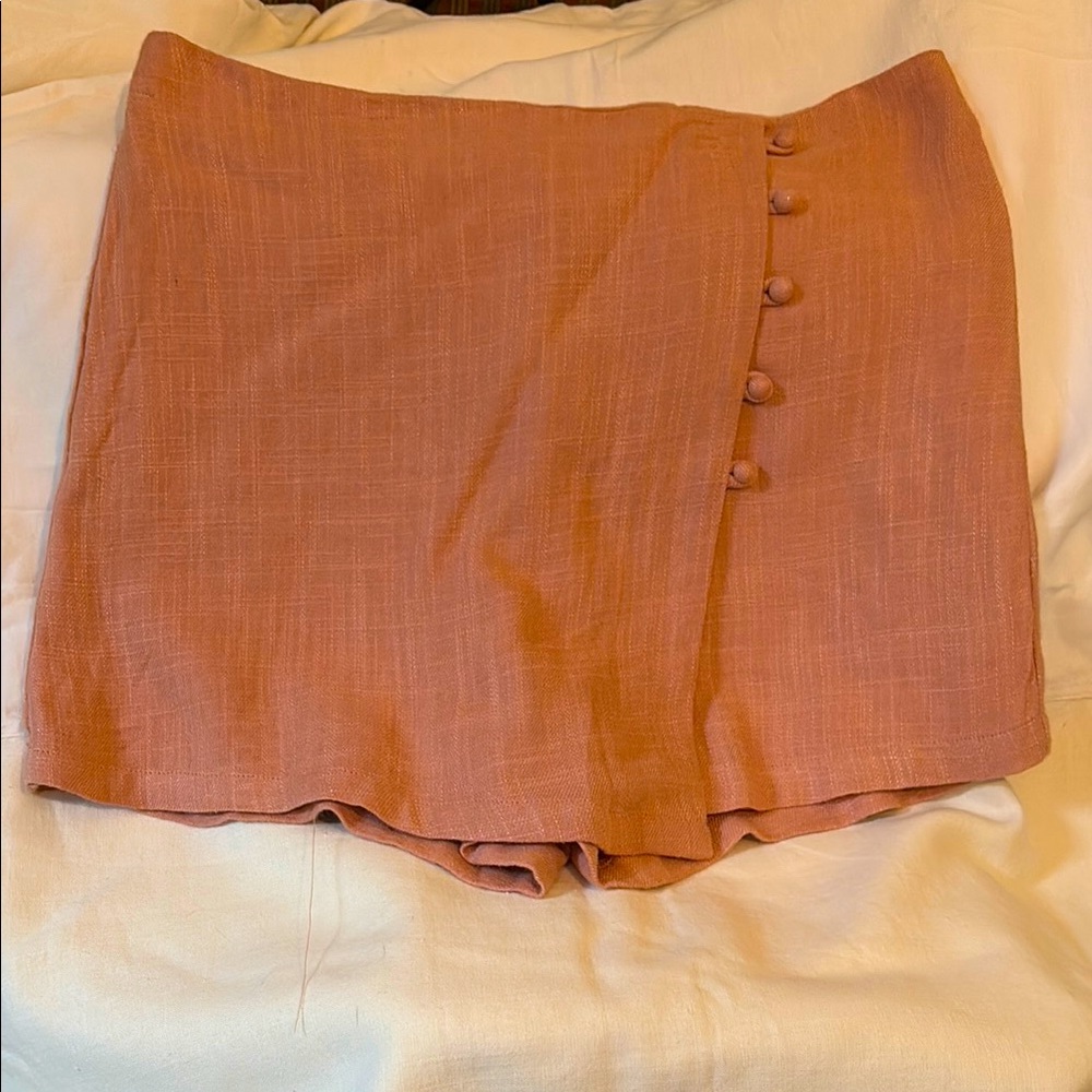 Peach colored skirt with cloth buttons in the front.
